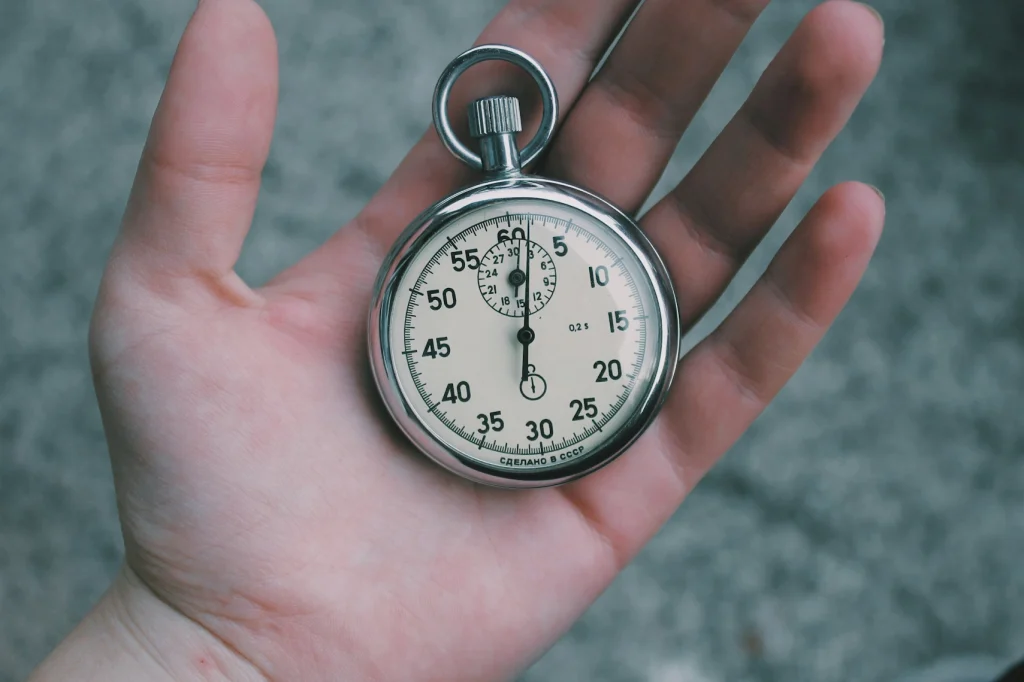 A pocket watch being held in a mans hand.